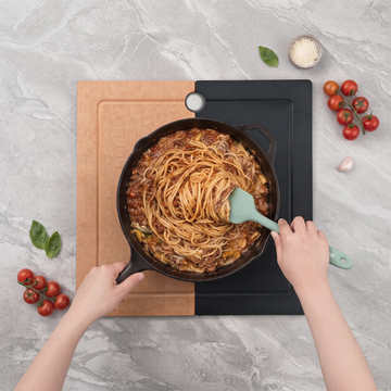 Cast iron pan of pasta resting on an Elihome Camper Series board over an RV kitchen sink