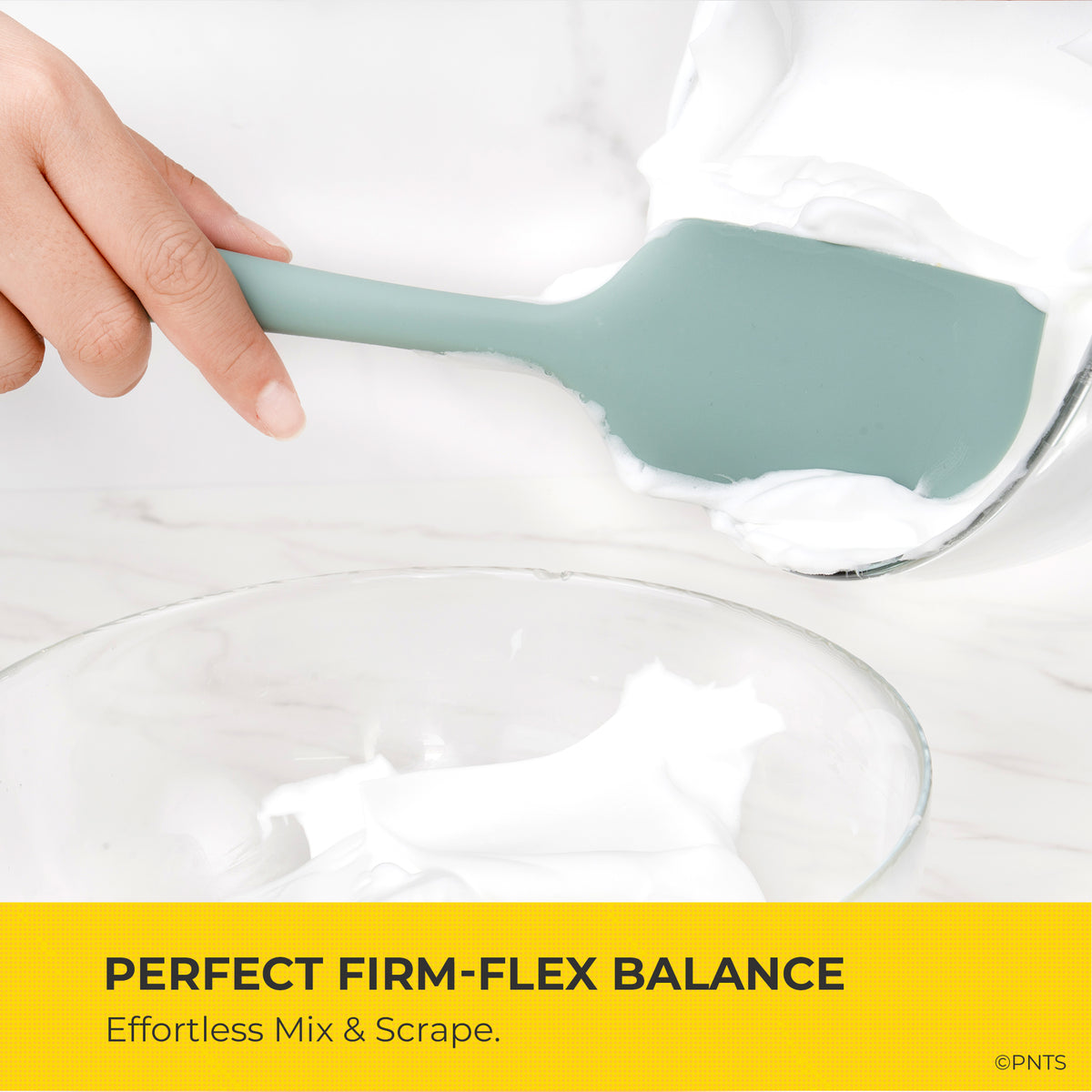 Silicone spatula being used to mix a white substance in a clear bowl with text about firm-flex balance.